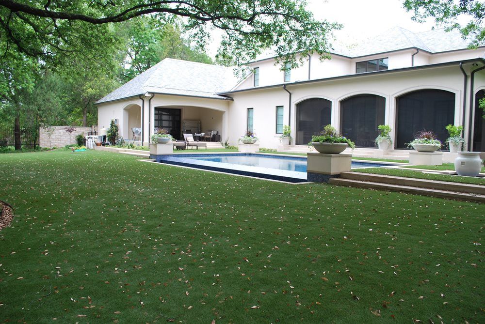 artificial turf in front of a house with a swimming pool